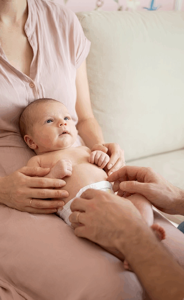 Paar hält sein Baby im Arm auf dem Sofa – ein ruhiger Moment nach der Kinderwunschzeit und symbolisches Bild für die virtuelle KinderwunschMesse.